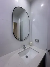 Lavatorio del baño compartido con espejo ovalado y tablero de cuarzo