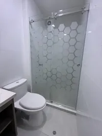 Baño principal con ducha de vidrio hexagonal