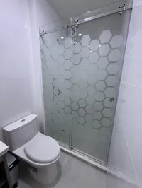 Baño propio de la Habitación 1 con ducha de vidrio hexagonal cerrada, inodoro y tablero de cuarzo