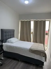 Habitación 2 con cortinas amplias y ventana con vista a la ciudad