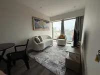 Sala amoblada con sofá crema curvo, sillón individual con cojín amarillo, cuadro decorativo del árbol y TV
